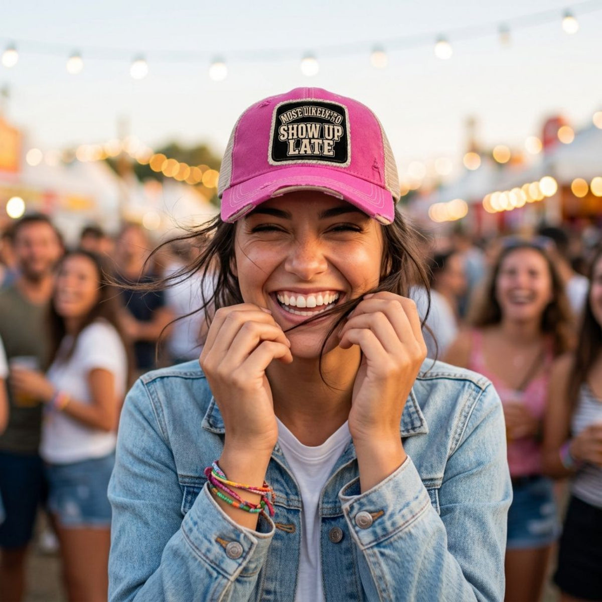 Woman at a music festival wearing the hot pink MOST LIKELY TO SHOW UP LATE trucker hat