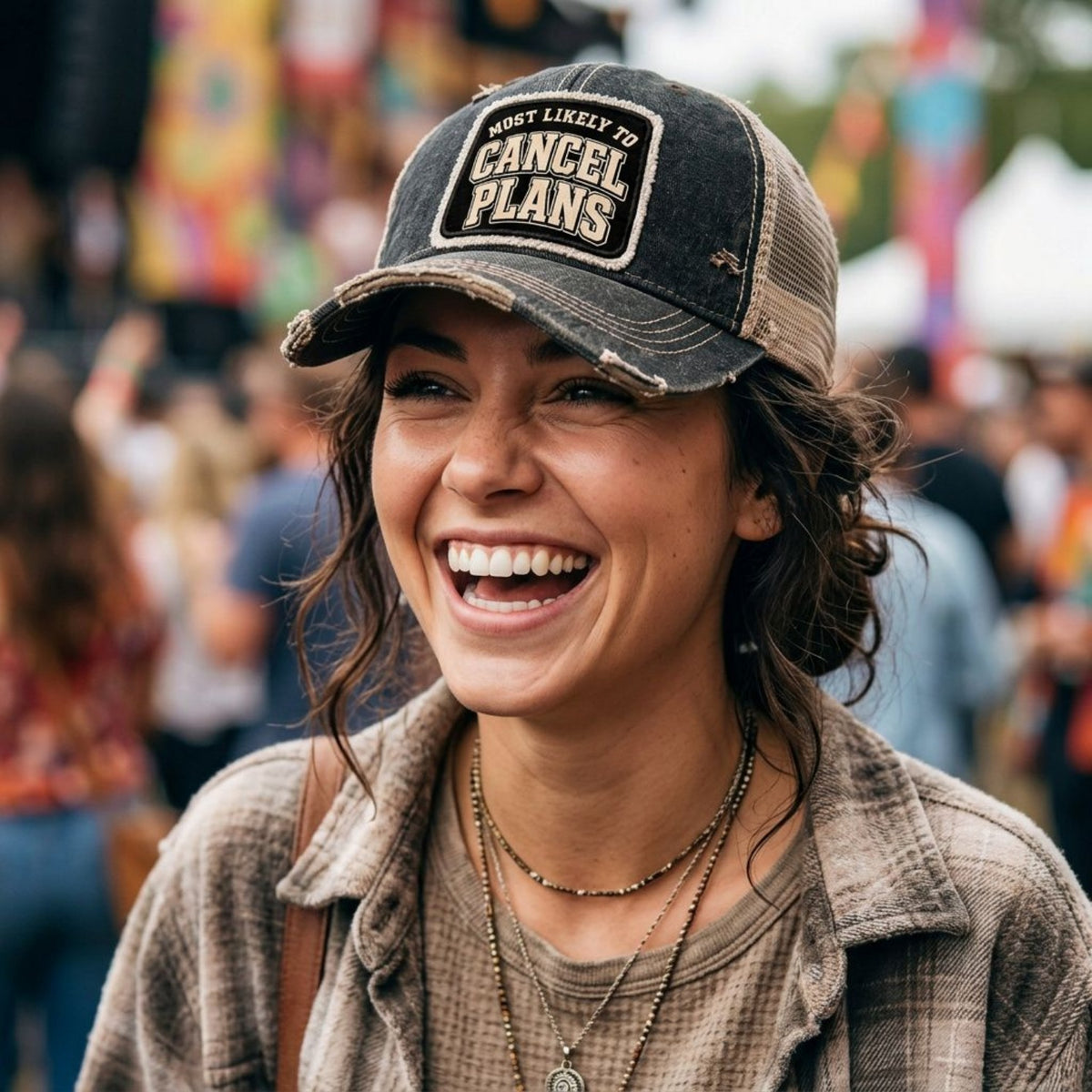 Woman laughing at a music festival wearing the black MOST LIKELY TO CANCEL PLANS trucker hat