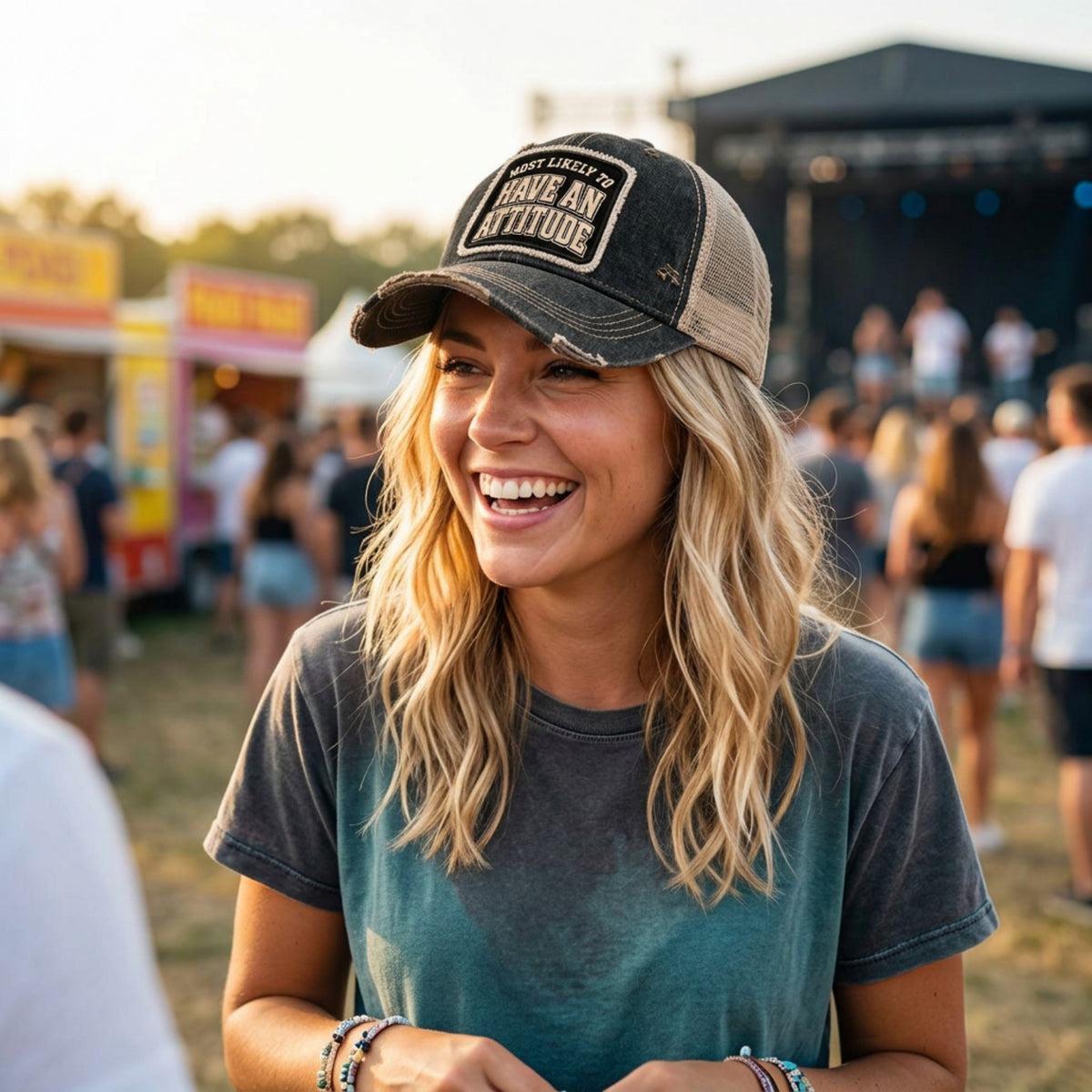 Woman at a music festival wearing the black MOST LIKELY TO HAVE AN ATTITUDE trucker hat